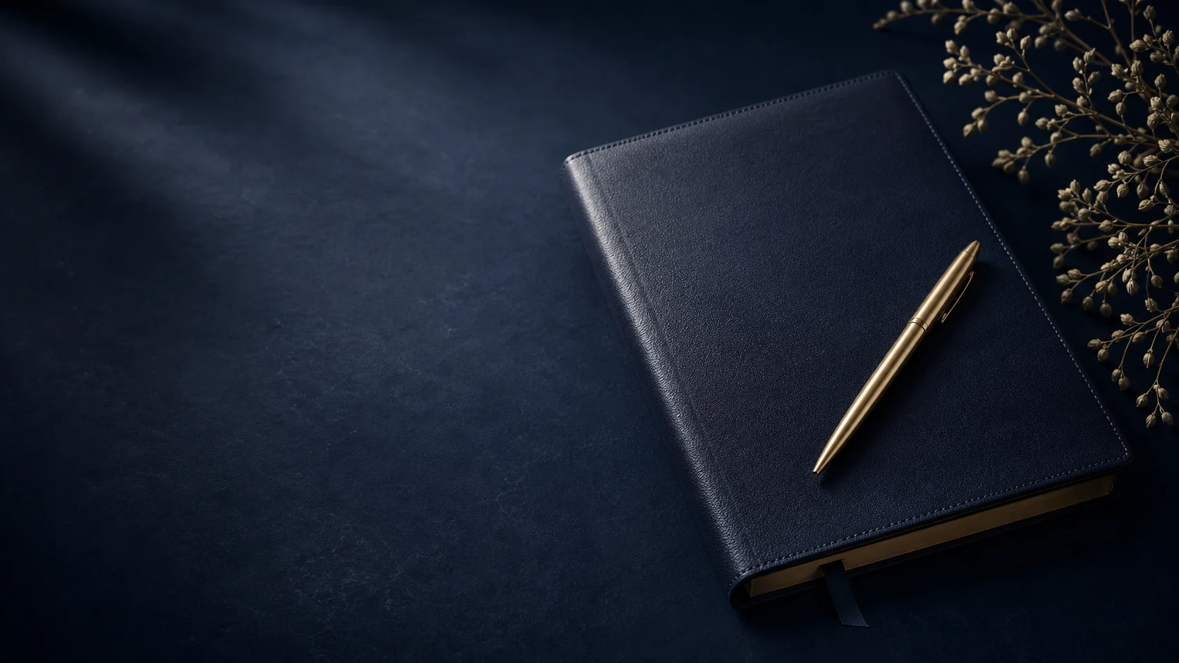 Dark navy leather accounting ledger with a brass pen and botanical branch